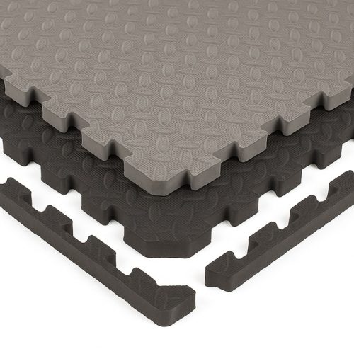 EVA foam interlocking floor tiles in grey and black, stacked in a stepped layout on a white background, showing the textured surface and puzzle-edge borders for home gym and playroom flooring.