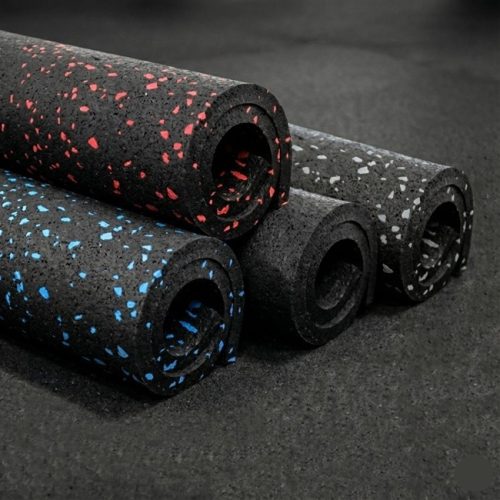 stacked rolls of rubber sports flooring on a plain black rubber gym floor
