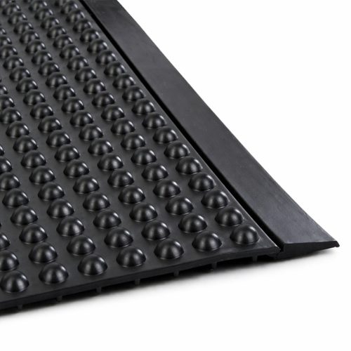 Close-up of a black anti-fatigue rubber mat with raised dome stud pattern and straight beveled edge on a white background.