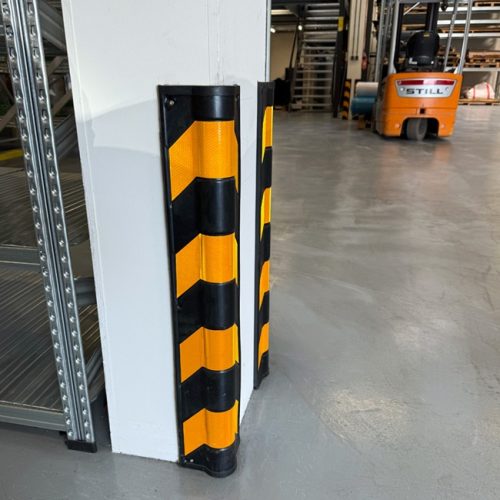 Rubber corner protector with black and yellow stripes installed on warehouse pillar for impact protection